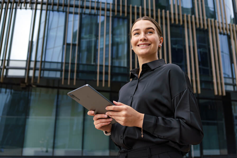 Young woman standing in front of a building holding an iPad