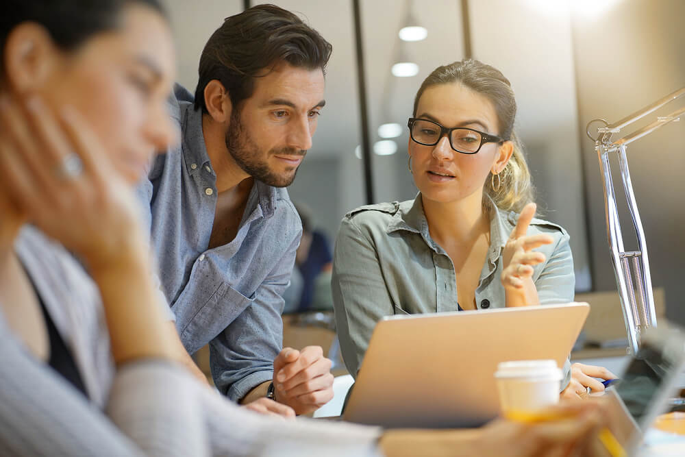 Three people working together round a laptop