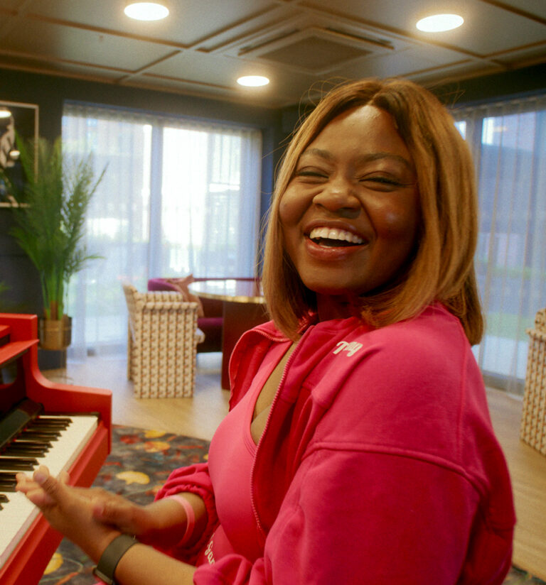 Young woman sat at piano laughing