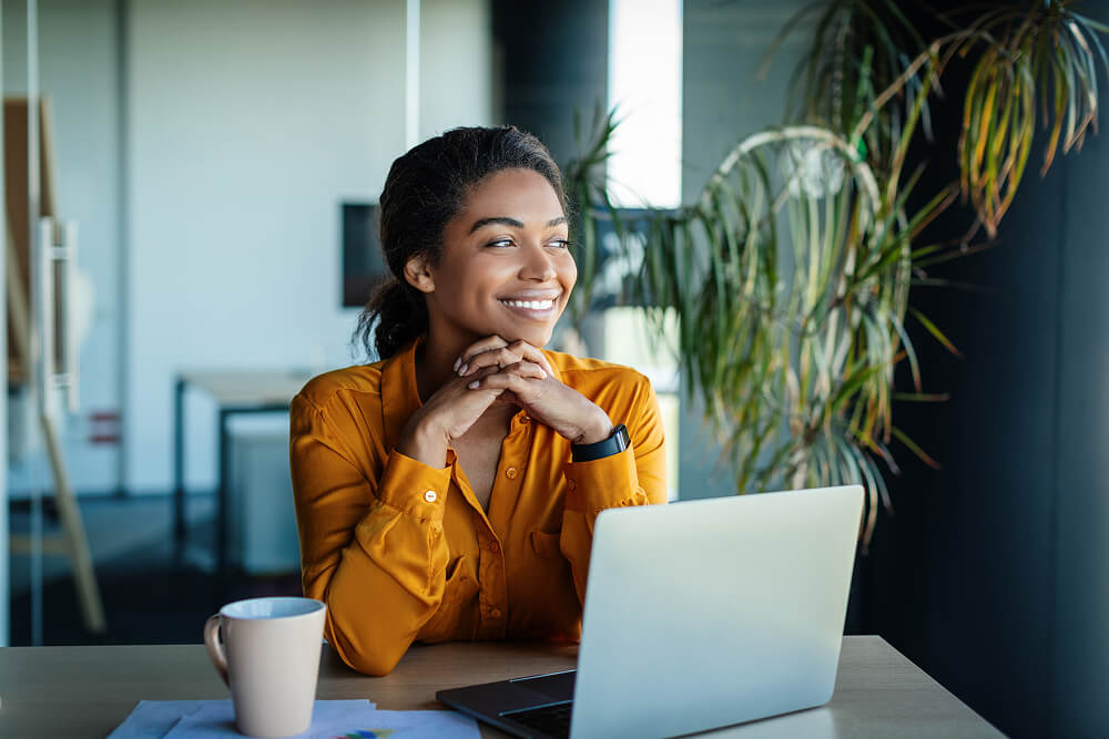 Young woman sitting in front of her laptop in an office, smiling