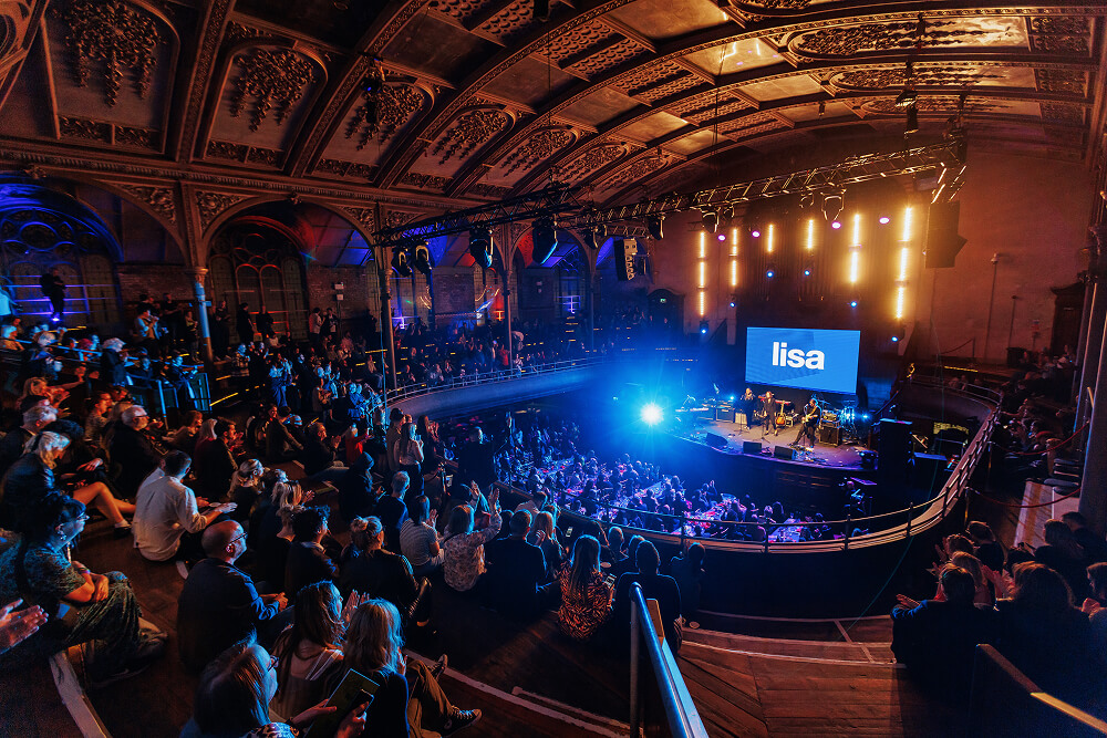 A picture of inside the Albert Hall in Manchester. Lots of audience members seated facing the stage